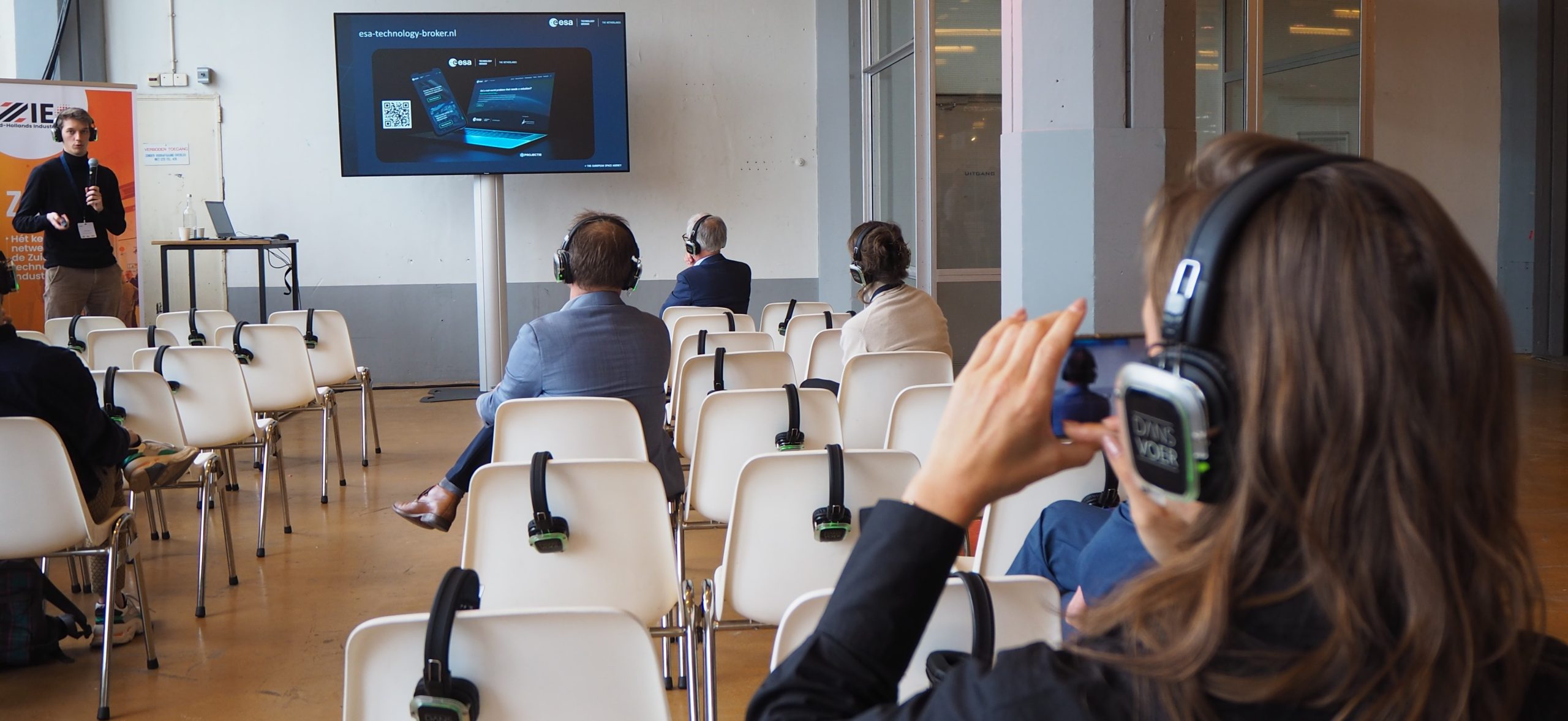 audience in auditorium style listing to presentation via headsets